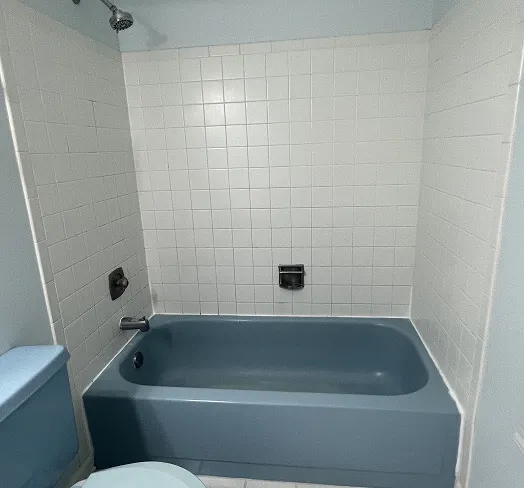 Professionally refinished blue bathtub with white ceramic tile surround in Queens