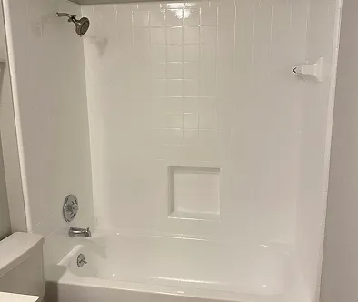 White bathtub with shower head and tiled wall.
