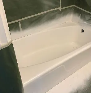 Bathtub being refinished with protective plastic and tape.