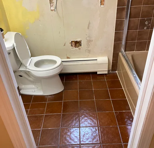 Bathroom with toilet, bathtub, and unfinished walls