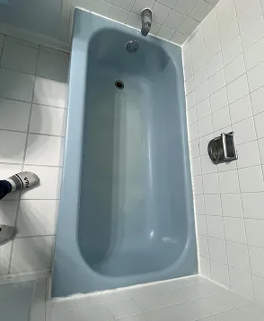 Blue bathtub with white ceramic tile surround in Queens