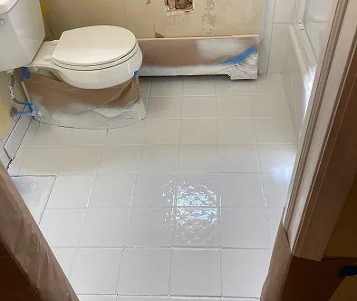 Bathroom renovation with freshly tiled floor and protected toilet and tub.