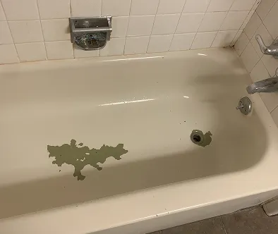 Damaged bathtub with peeling enamel and rust stains