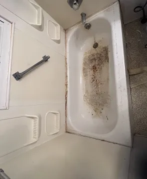 Bathtub before professional reglazing with visible stains and wear in Queens