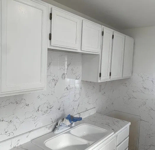 White kitchen cabinets with a marble-patterned backsplash and countertop.
