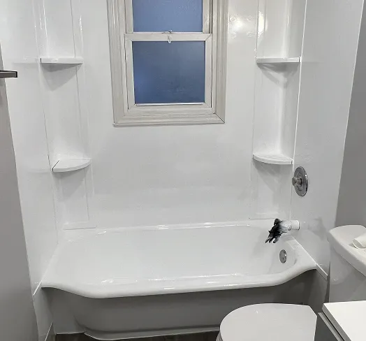 Professionally refinished white bathtub and shower surround with built-in shelves in Queens