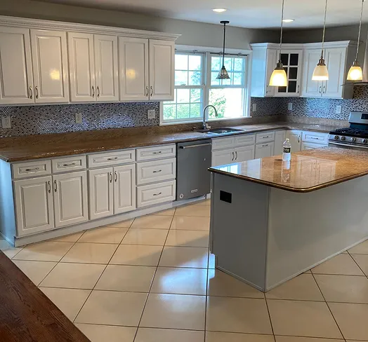 Kitchen with white cabinets, granite countertops, stainless steel appliances, and a large island.