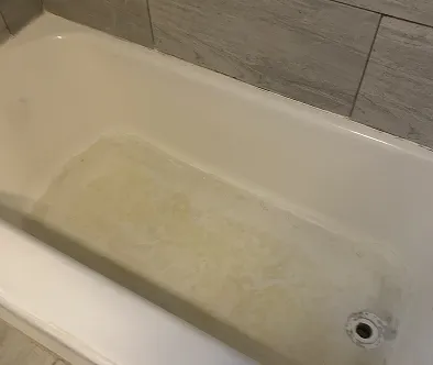 Dirty bathtub with water stains and tiled wall
