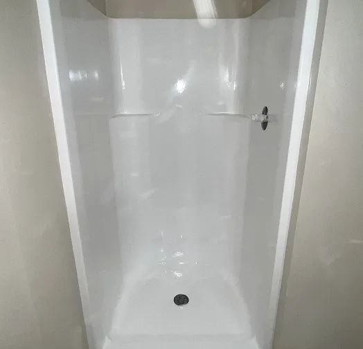 White shower stall with drain and faucet fixture