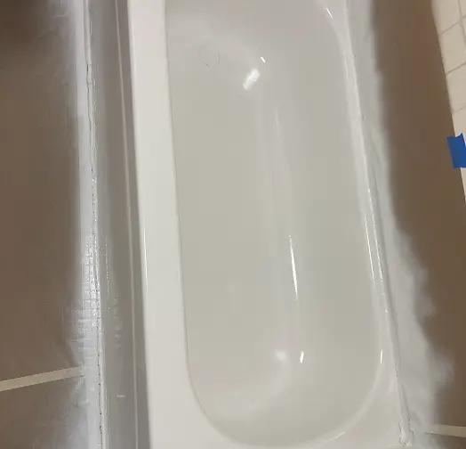 White bathtub with blue painters tape on the edge.