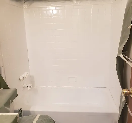 Freshly reglazed white bathtub with glossy shower tile walls in Bronx
