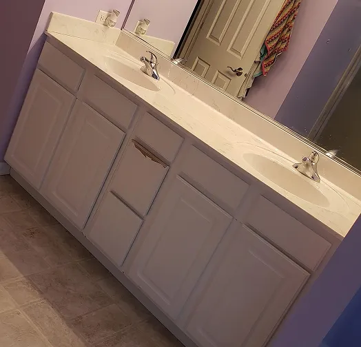 Double sink vanity with white cabinets and marble countertop.