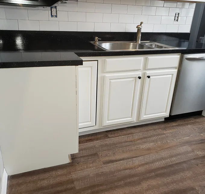 Kitchen counter with sink, white cabinets, and stainless steel dishwasher.