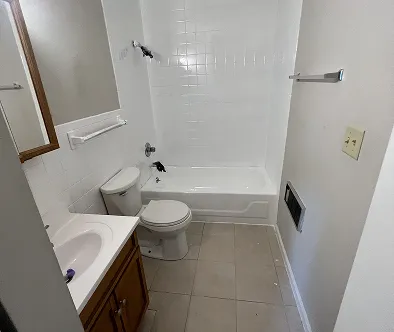 Bathroom with toilet, sink, and bathtub with white tiled walls.
