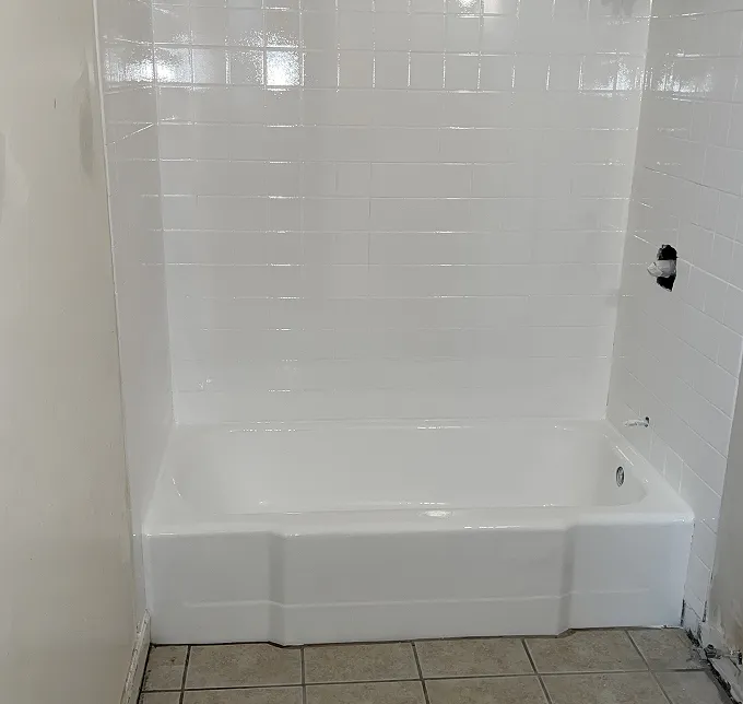 Freshly reglazed white bathtub with glossy subway tile surround in Bronx