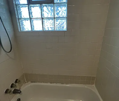 Bathtub with tiled walls and a glass block window