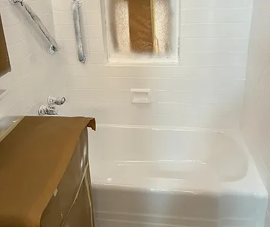 White bathtub with chrome fixtures and a window covered with brown paper.