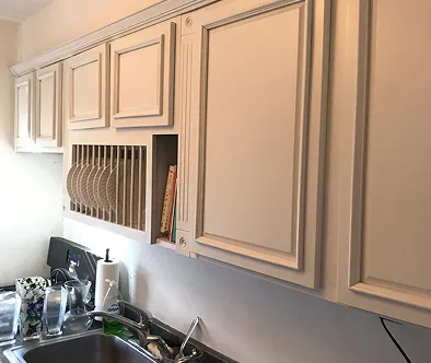 Kitchen cabinets with a built-in plate rack and a small shelf holding books.