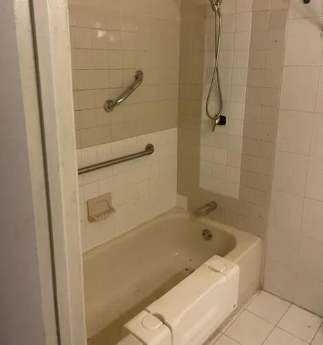 Bathroom with bathtub, shower, and grab bars