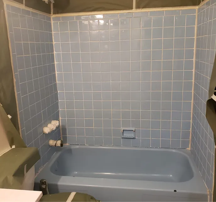 Light blue tiled shower and bathtub with soap dish.