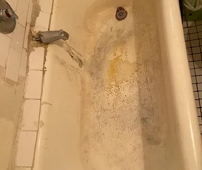 Dirty bathtub with mold and rust stains